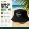 Same-day black Bells bucket hat with custom front print on a beach background