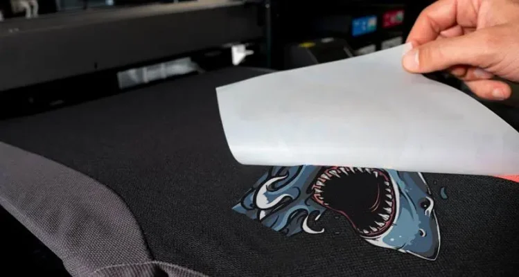 DTF transfer being peeled from a custom printed garment after heat pressing