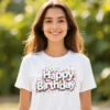 Woman wearing the Happy Birthday ladies t-shirt in white while standing in a park