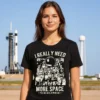 Woman wearing a black I Really Need More Space Ladies T Shirt standing in front of a rocket launch pad