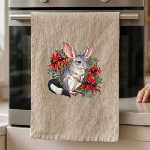 Lifestyle photo of the Bilby Among Sturt Desert Peas Tea Towel being worn or used