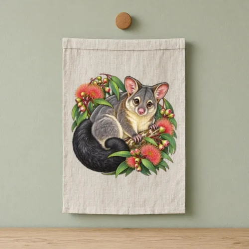 Natural linen Brushtail Possum Among Eucalyptus Blooms tea towel hanging from a timber peg on a pale green kitchen wall