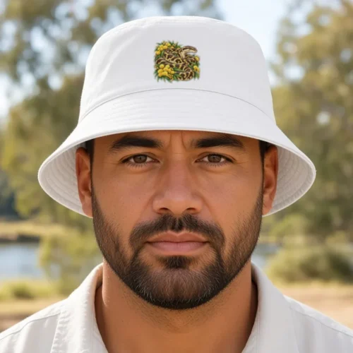 Man with a dark beard at a riverside picnic spot, wearing the white Carpet Python Among Golden Wattle bucket hat