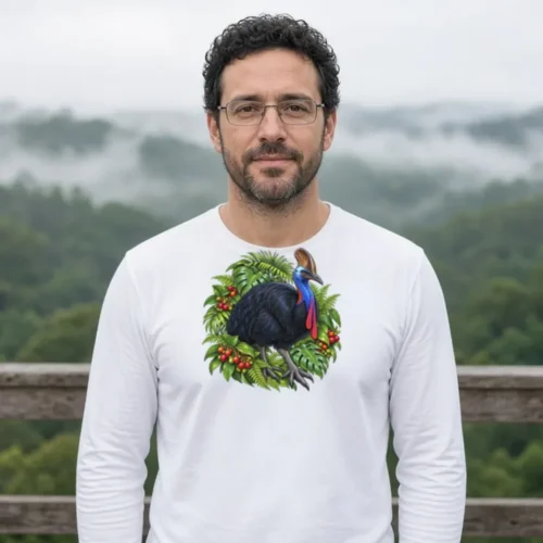 Man with curly dark hair and glasses by a misty tableland lookout, wearing the white Cassowary Among Rainforest Foliage long sleeve T-shirt